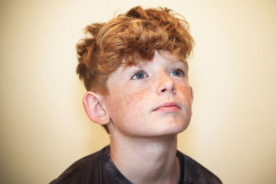 Close-up portrait of boy looking away against white background