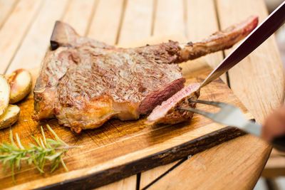 Close-up of meat on cutting board over wooden table