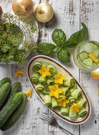 Flat lay of plate with cut cucumbers and ingredients on the table 