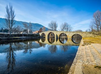 Arch bridge over river against sky