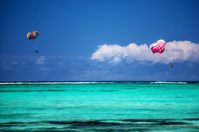 People paragliding over sea against sky