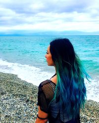 Rear view of woman with dyed hair at beach against sky