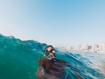 Man against blue sea against clear sky