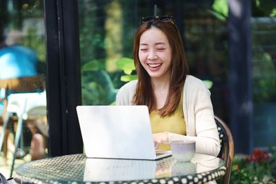 Portrait of young woman using phone while sitting at park