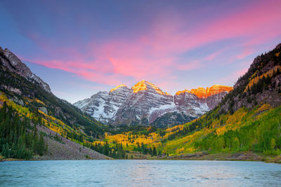 Scenic view of lake by mountains against sky during sunset