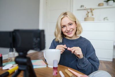 Portrait of young woman using mobile phone at home