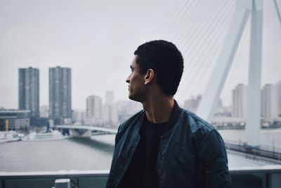 Young man looking at city buildings against sky