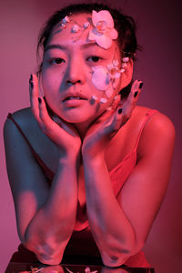 Portrait of young woman with petals on face