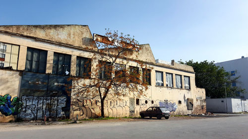 Abandoned building by street against clear sky