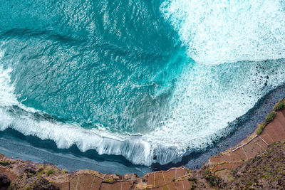 High angle view of sea waves splashing on rock