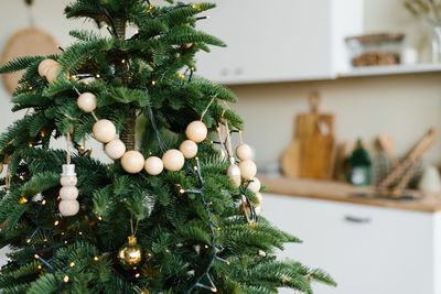 Stylish wooden beads on a christmas tree in the dining room of a scandinavian home