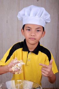 Portrait of cute boy wearing chef hat preparing food in kitchen at home