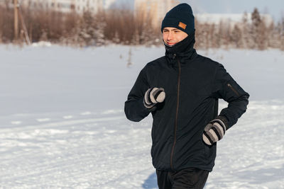 Rear view of man skiing on snow covered field