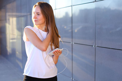 Portrait of young woman standing against wall