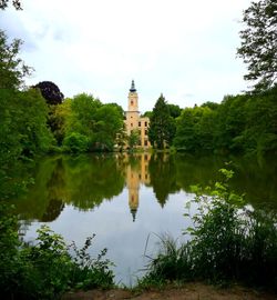 Reflection of trees and building in lake against sky