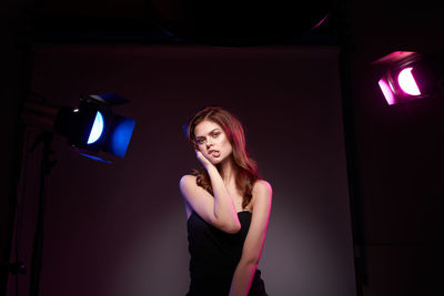 Portrait of young woman standing against wall