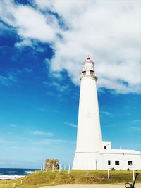 Low angle view of lighthouse by building against sky