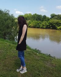 Rear view of woman standing by tree against lake