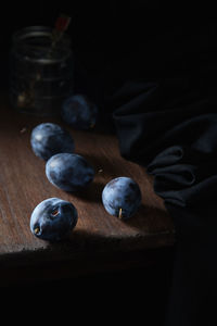 Blue plum on a wooden table against the background of a glass jar