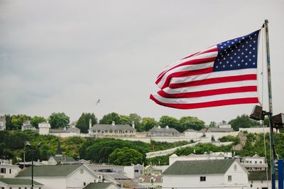 Close-up of american flag in city against sky