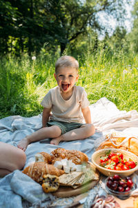 Boy child preschooler on a picnic. smiles, eating cherries and enjoying summer.