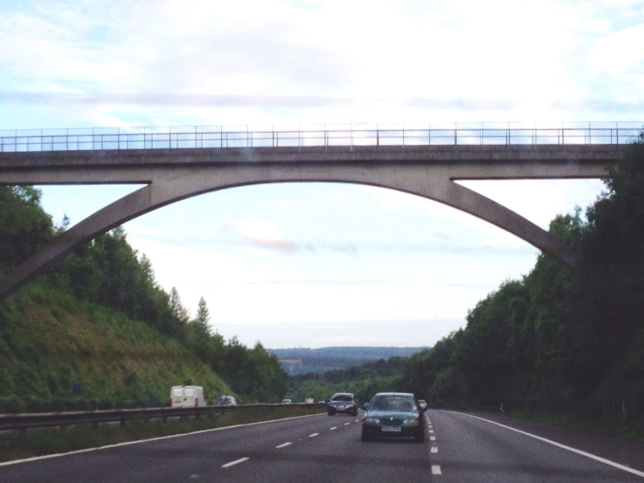 CARS ON BRIDGE OVER ROAD AGAINST SKY