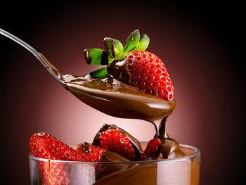 Close-up of strawberries in glass on table against black background