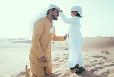 Side view of couple standing on beach