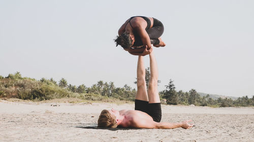 Man and woman doing yoga at beach