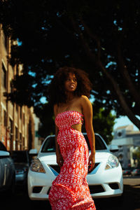 Portrait of smiling young woman standing by car