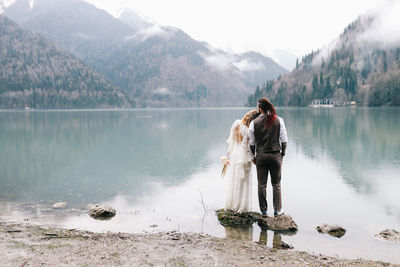 Rear view of men on lake against mountains