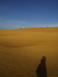 Shadow of person on sand dune in desert against sky