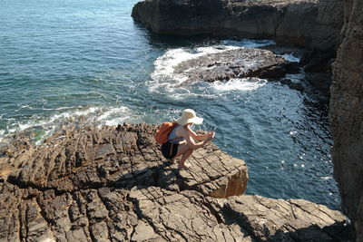 High angle view of woman sitting on rock at beach