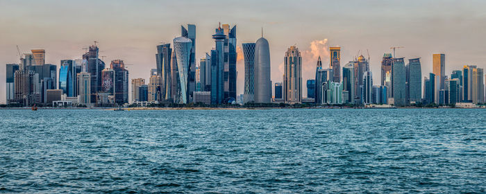 Doha skyline daylight view with arabic gulf in foreground and clouds in the sky in background 