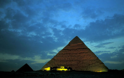 Old stone pyramids on desert landscape against sky