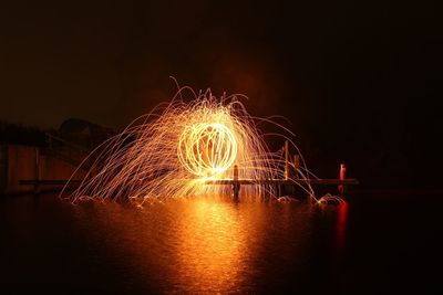 Firework display over lake against sky at night