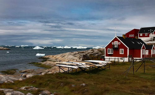 Houses by sea and buildings against sky