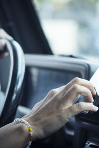 Cropped hand of man using mobile phone in car