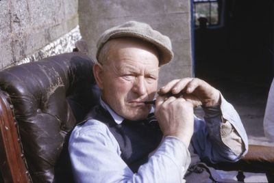 Portrait of man sitting on chair against wall