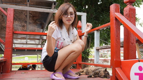 Portrait of young woman crouching by cat