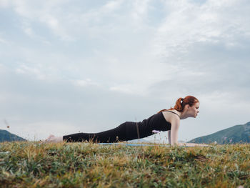 Side view of young woman on field against sky