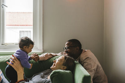 Parents with baby girl sitting on sofa