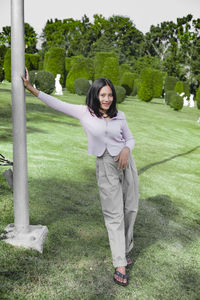 Portrait of smiling young woman standing on field