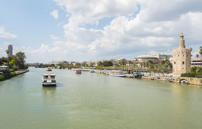 Buildings by river against sky