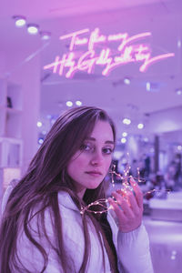 Portrait of young woman holding illuminated glass