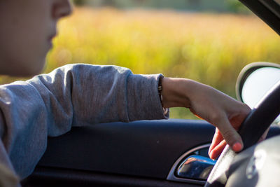 Midsection of young woman driving car