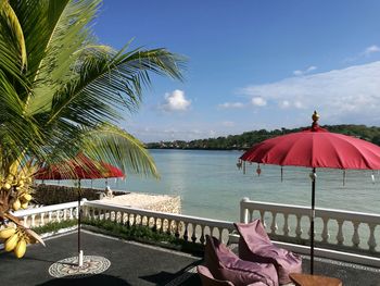 Lounge chairs by swimming pool at beach against sky