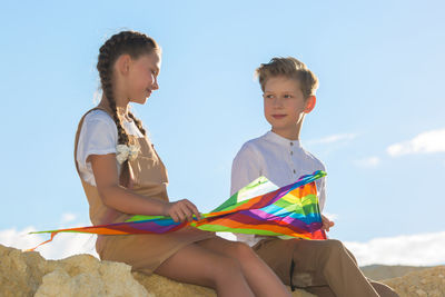 Teenage friends met in nature, talking and collecting a kite.