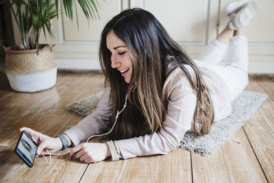 Beautiful woman having video call with friend while lying on floor at home