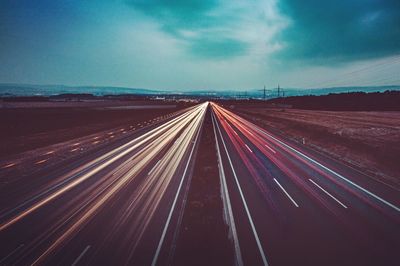 Light trails on highway against sky